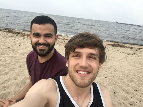 Dois amigos sentados na areia da Pria do Laranjal. À frente, um rapaz loiro sorridente; logo ao fundo, um moreno (eu).