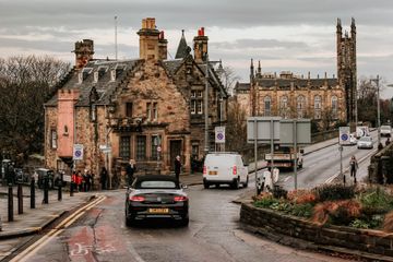 Uma rua de Edimburgo, na Escócia, com alguns veículos e pedestres.