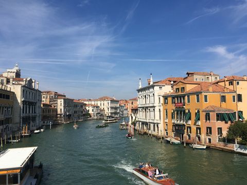 Grande Canal, em Veneza. Algumas embarcações passam pelo canal. Ambas as margens são preenchidas por edifícios antigos.