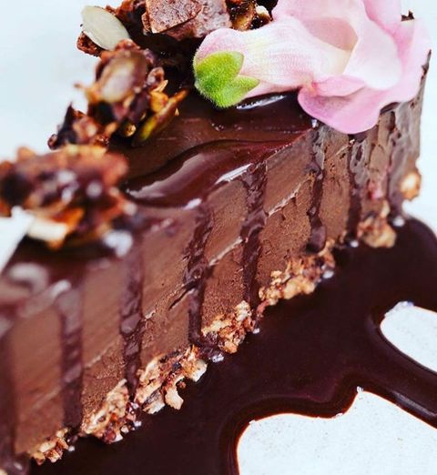 Torta crua de chocolate, com uma flor rosa e outros enfeites no topo.