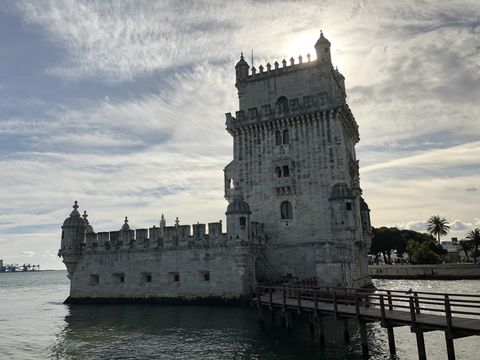 Uma torre quadrada bastante trabalhada no topo. Em um dos lados, um espaço murado. A torre está no meio de uma área alagada. Para chegar até ela, há uma travessia em madeira a partir do lado direito da imagem.