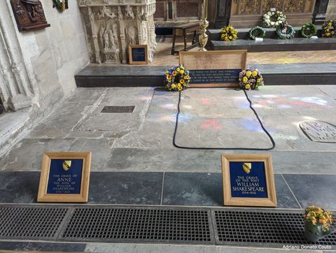 Estamos no interior de uma igreja e vemos, bem de perto, dois túmulos. No da esquerda, está Anne, esposa de Shakespeare; à direita, o próprio William Shakespeare. O túmulo da direita possui flores amarelas depositadas.