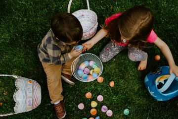 Crianças brincam com ovos de plástico sobre um gramado na ocasião da Páscoa. Foto pot Gabe Pierce em Unsplash.com