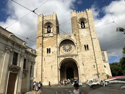 Um pouco acima em uma colina, uma igreja de linhas retas, com duas torres quadradas e uma grande rosácea no centro. Logo abaixo, uma grande porta central. Há muitos cabos de bondinho na frente.