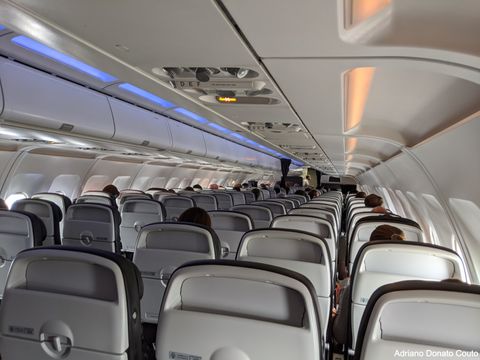 Voo Londres–Amsterdã, com ocupação alternada de assentos e todos sentados aguardando permissão para desembarcar.