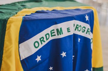 Uma bandeira brasileira posta como uma toalha sobre uma mesa. Close na área do disco azul do centro.