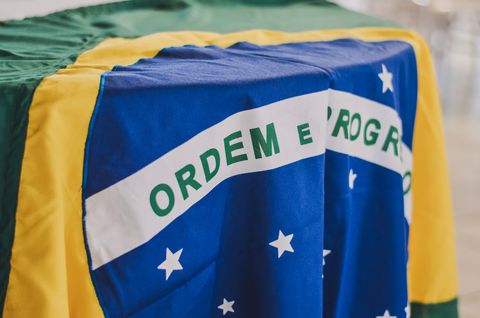 Uma bandeira brasileira posta como uma toalha sobre uma mesa. Close na área do disco azul do centro.