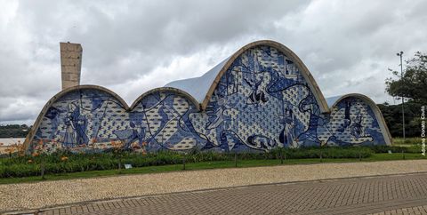 Em uma série de arcos que lembram montanhas, vemos um painel de azulejos em azul e branco. Eles retratam São Francisco e outras figuras. É a estrutura de uma igreja, com uma torre à esquerda.