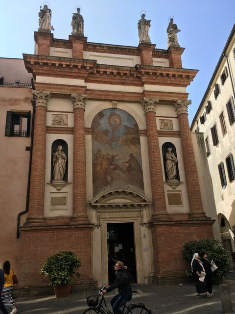 Igreja de San Canziano, em Pádua. Templo cor creme, com quatro colunas de tijolos vermelhos. Há uma estátua cinza de cada lado (entre as colunas) e quatro estátuas no topo. Há também uma pintura no topo, ao centro, retratando Nossa Senhora da Imaculada Conceição nos Céus, rodeada de santos.