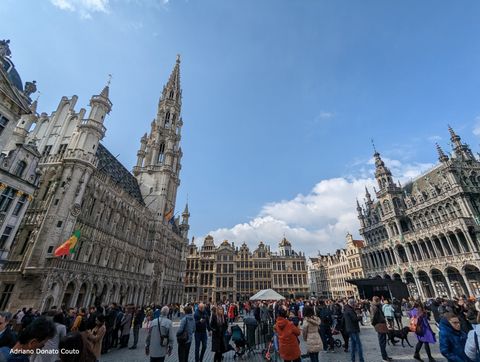 Vê-se uma grande multidão, rodeada de fileiras de edifícios históricos em diferentes estilos arquitetônicos.