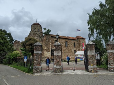 Quatro pilares quadrados conduzem a vista a um castelo medieval de pedra ao fundo. Há algumas árvores ao seu redor.
