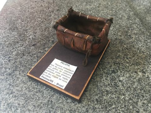 Incensário marrom simulando uma embarcação indígena. O formato lembra um cesto de couro.