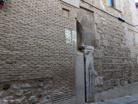 Em uma fachada antiga de cor marrom, vemos parte de um arco mouro e uma coluna visigoda encrustados no meio da estrutura.