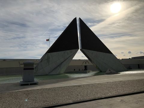 Sobre um espelho d'água, vê-se duas vigas robustas de metal se encontrarem, saindo a partir da água em direção diagonal. Há um corte em 45 graus na ponta, para que elas se alinhem na área em que quase se tocam.