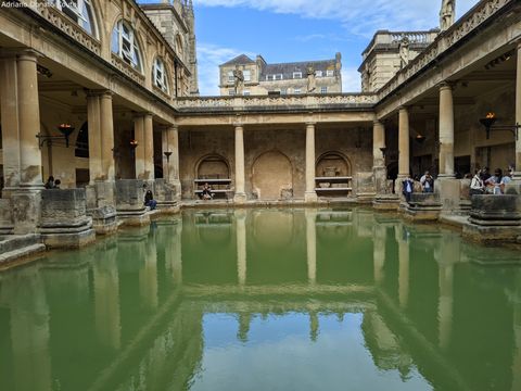 Termas romanas, com enorme piscina esverdeada ao centro, ladeada por passagens cobertas, que são sustentadas por grossas colunas de pedra.