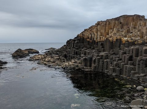 Em uma área costeira, uma série de colunas hexagonais de rocha formam um penhasco.