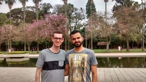 Em primeiro plano, dois rapazes (eu incluso). Logo atrás, um espelho d'água; ao fundo, um gramado cheio de árvores.