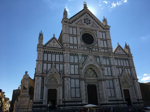 Basílica em três naves, cada uma com uma porta. A fachada é branca com detalhes em faixas verdes. No topo, um detalhe redondo que parece ser uma rosácea, com uma estrela de seis pontas logo acima. O céu tem poucas nuvens.